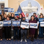 Advocates and legislators hold signs that say "Food4All."